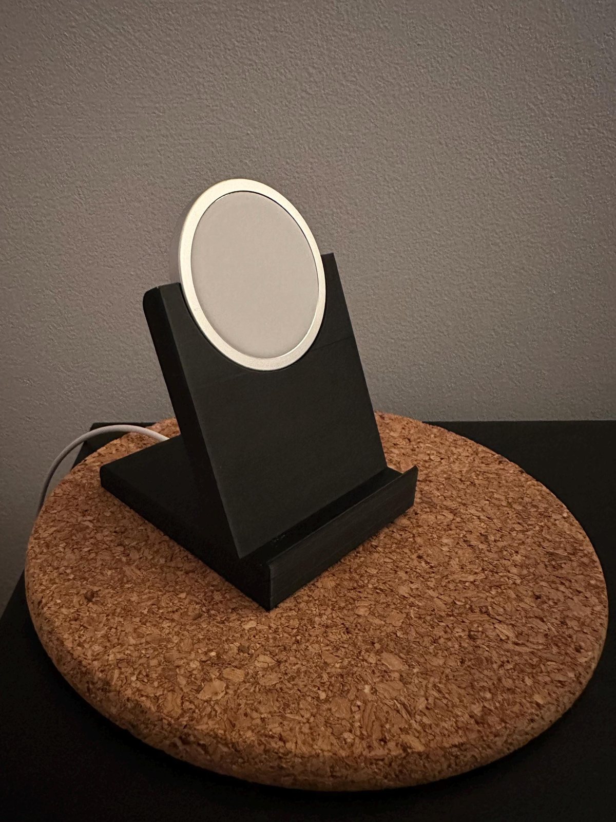 Black 3D-printed phone stand holding a round MagSafe charger